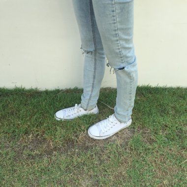 Kız bacaklar arka plan üzerinde beyaz spor ayakkabı 