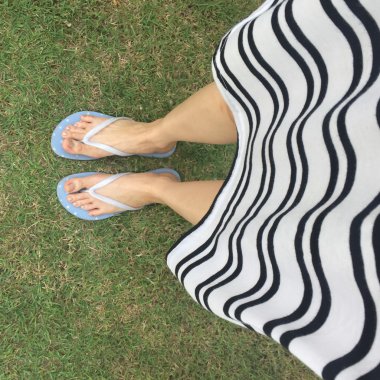 Tatlı parlak flip flop ve bacak yeşil çimenlerin üzerinde 