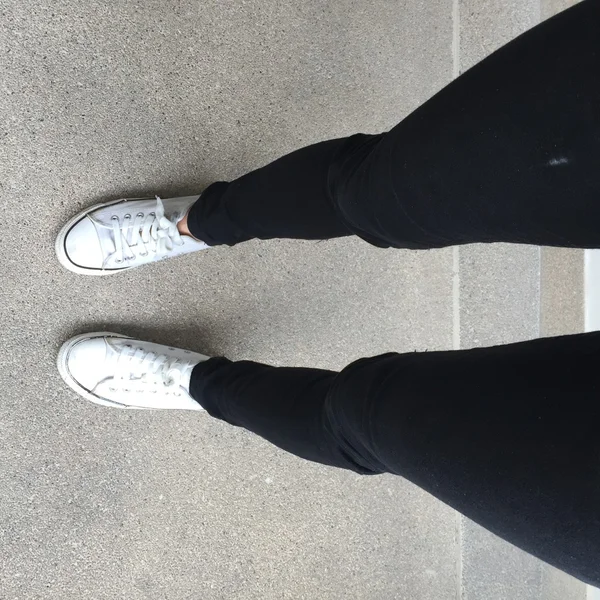 Vita sneakers på flicka ben i bakgrunden — Stockfoto