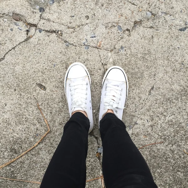 Kız bacaklar arka plan üzerinde beyaz spor ayakkabı — Stok fotoğraf