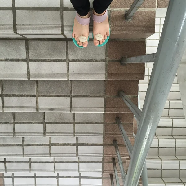 Женщина ноги и ноги в шлепанцах стоять на открытой лестнице от первого лица вид — стоковое фото