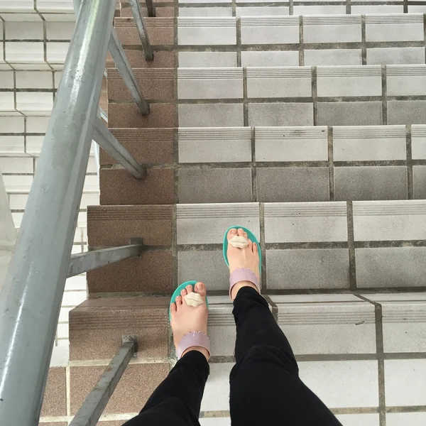 Jambes et pieds de femme en tongs debout sur les escaliers extérieurs vue à la première personne — Photo