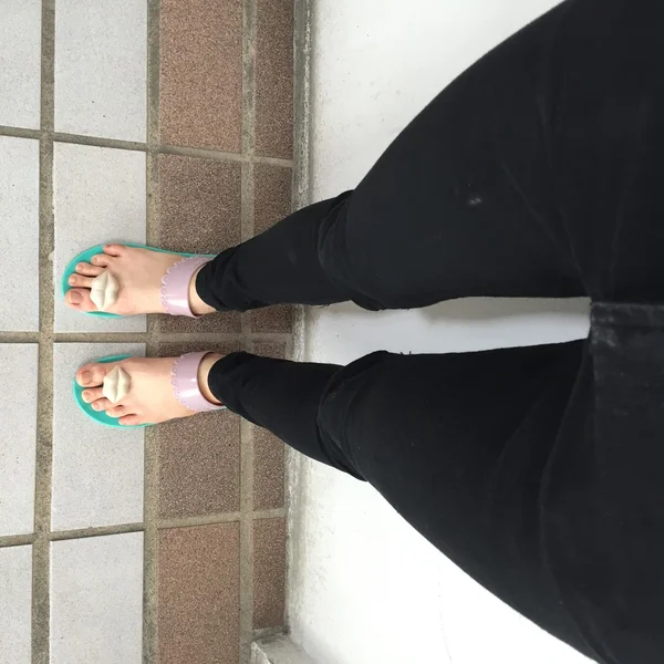 Baixa seção de mulher usando chinelos verde de pé na caminhada no chão — Fotografia de Stock