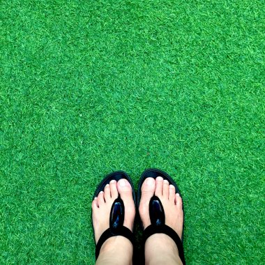 Yeşil yemyeşil suni çim, yaz ve tatil konsepti siyah Flip flop 