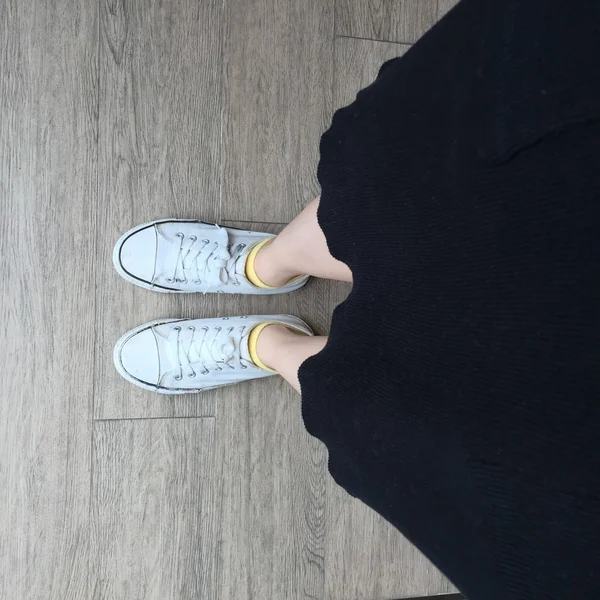 Image de mode extérieure des jambes de la femme, portant une robe élégante et des baskets blanches — Photo