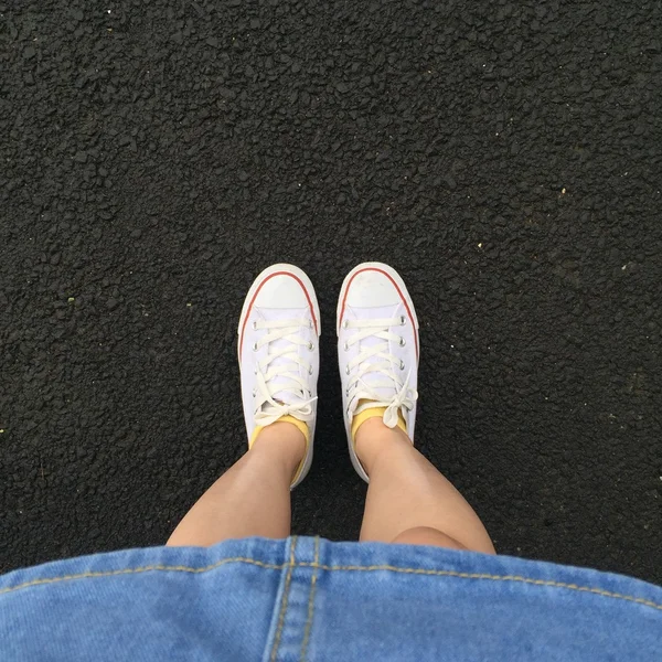 Close up of legs woman with dress jean and white sneakers outdoor — Stock Photo, Image