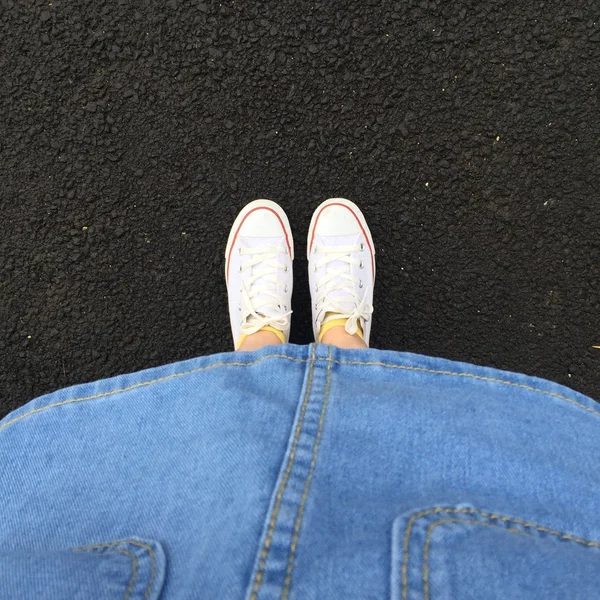 Cierre de piernas mujer con vestido jean y zapatillas blancas al aire libre — Foto de Stock