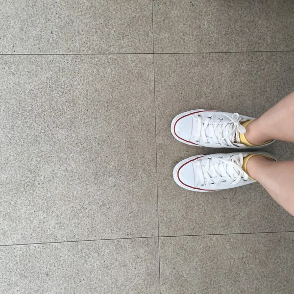 Närbild på benen kvinna med ben och vita sneakers utomhus — Stockfoto