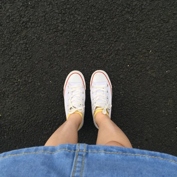 Bacaklar kadın elbise jean ve beyaz spor ayakkabı açık ile yakın çekim — Stok fotoğraf