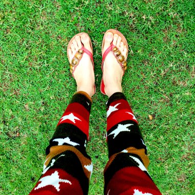 Giyen kadın bacakları çimenlerin üzerinde floplar flip. üstten görünüm