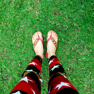 Giyen kadın bacakları çimenlerin üzerinde floplar flip. üstten görünüm