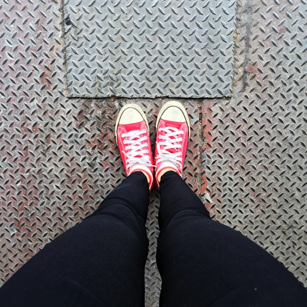 Zapatillas Rojas. Las Piernas De La Mujer En Zapatillas De Deporte Rojas Y  Pantalones Vaqueros Azules En El Fondo Del Piso Ideal Para Cualquier Uso.  Fotos, retratos, imágenes y fotografía de archivo