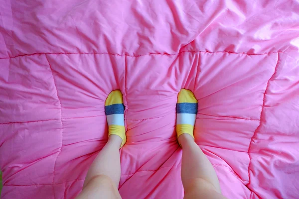 Дівчина з жовтими смугастими шкарпетками, спить у ліжку — стокове фото