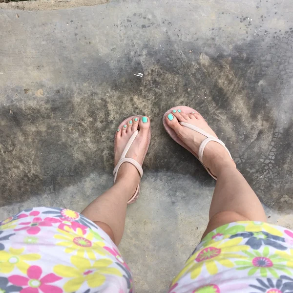 女性の足を着用フリップフロップとショートパンツ (花) 地面や床に.上面図 — ストック写真