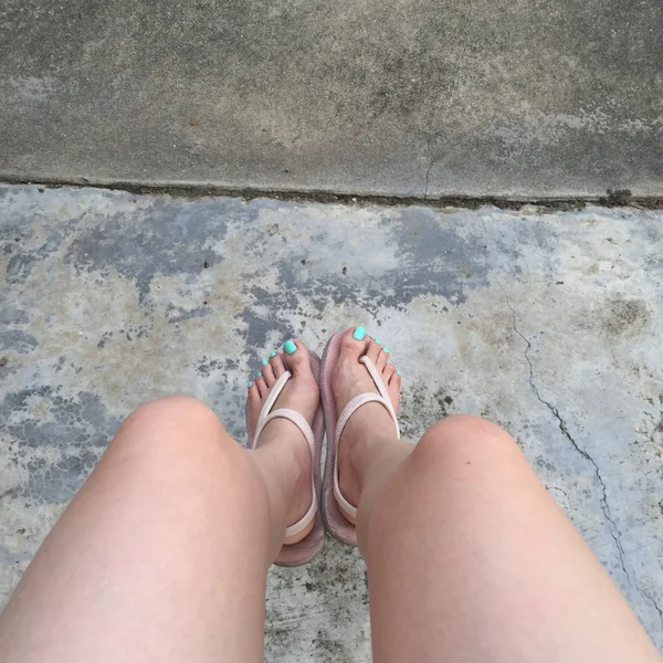 Kvinnliga ben bär flip flop och korta byxor (blomma) på mark eller golv. Topp-vy — Stockfoto