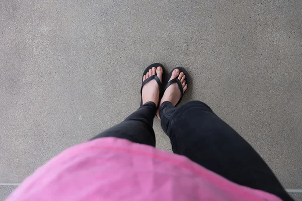 Ung flicka ben i svart Flipflop sandaler på golvet eller Grunge — Stockfoto