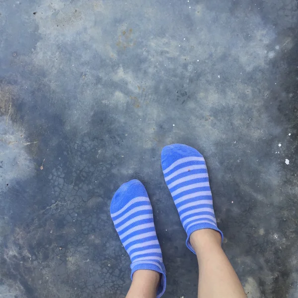 Fille avec des chaussettes à rayures bleues au sol ou au sol — Photo