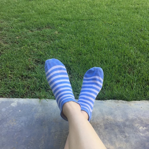 A teenager lays in the grass with her funky socks on with room — Stock Photo, Image