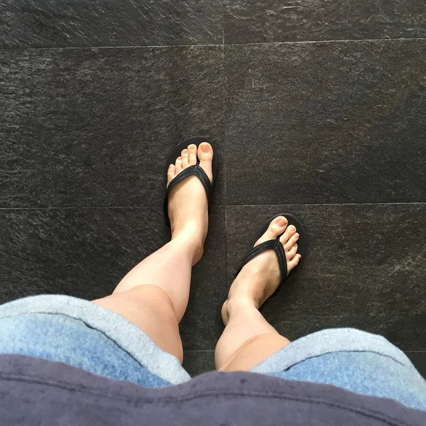 Mladá dívka nohy v černých Crocs sandály na podlahu nebo Grunge — Stock fotografie