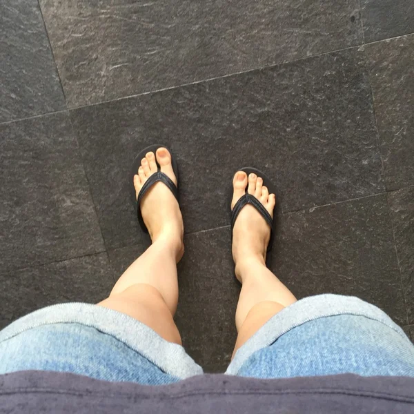 Mladá dívka nohy v černých Crocs sandály na podlahu nebo Grunge — Stock fotografie