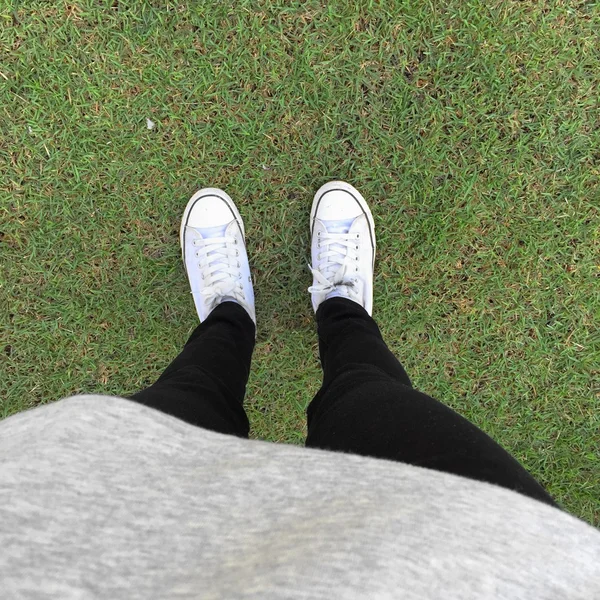 Pés em tênis na grama verde — Fotografia de Stock