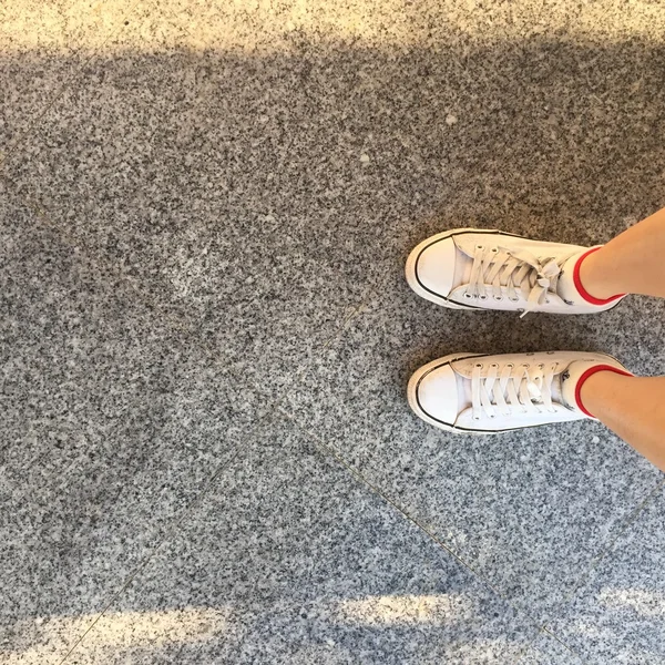 Білі кросівки на дівчачих ногах на фоні графіті — стокове фото