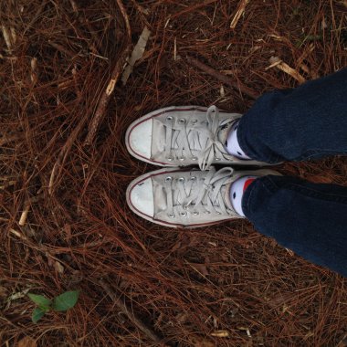 Kız bacaklar ahşap arka plan üzerinde beyaz spor ayakkabı