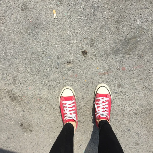 Röda sneakers skor Walking på Dirty Concrete topp vy — Stockfoto