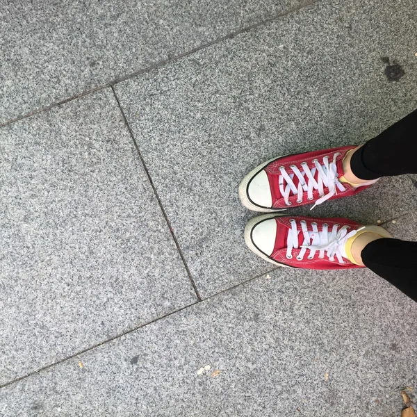 Obuv z červené tenisky chůze po špinavém betonu horní pohled — Stock fotografie