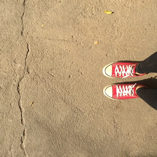 Sapatos de tênis vermelhos andando na vista superior de concreto sujo — Fotografia de Stock