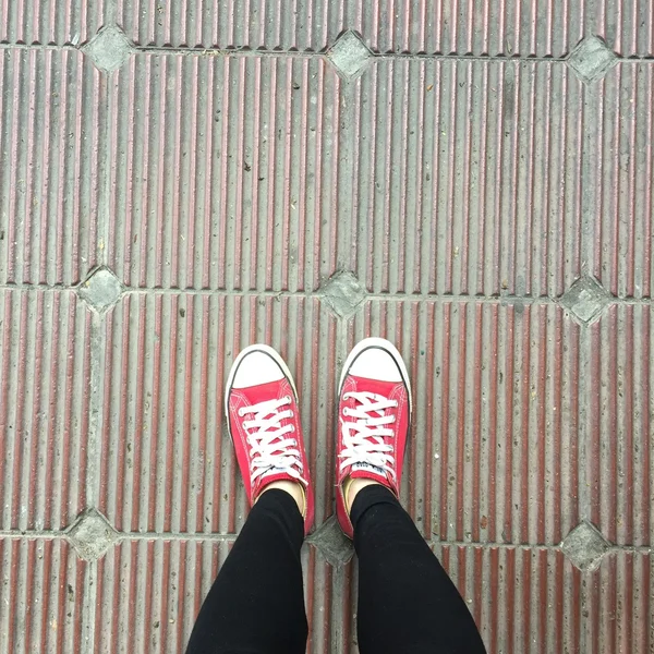 Zapatos rojos de las zapatillas que caminan en la vista superior sucia del hormigón —  Fotos de Stock