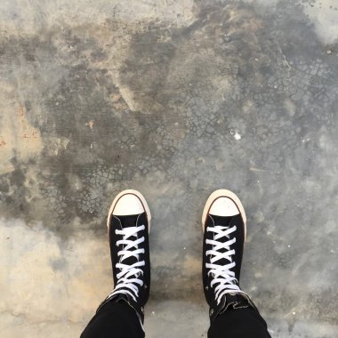 Kız ayak üzerinde siyah spor ayakkabı. Kadın siyah kot pantolon ve spor ayakkabı