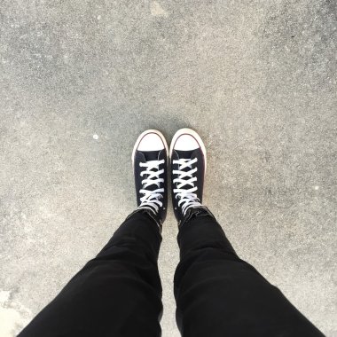 Kız ayak üzerinde siyah spor ayakkabı. Kadın siyah kot pantolon ve spor ayakkabı