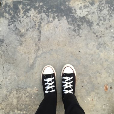 Kız ayak üzerinde siyah spor ayakkabı. Kadın siyah kot pantolon ve spor ayakkabı