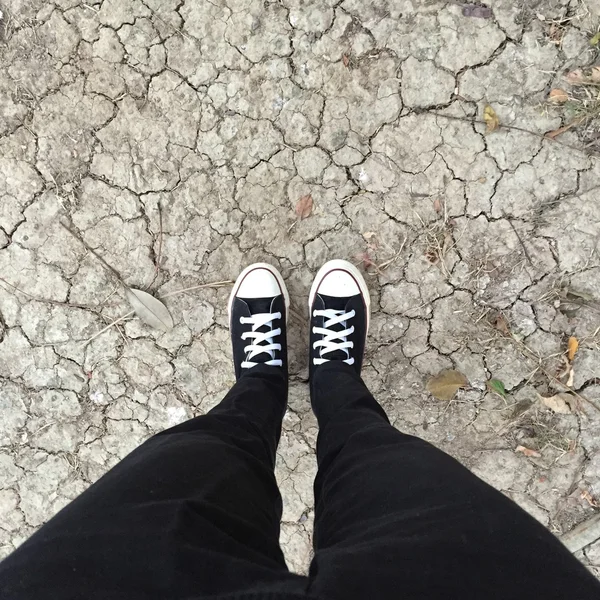 Sapatilhas pretas em pernas de menina. Mulher de calça preta e tênis — Fotografia de Stock
