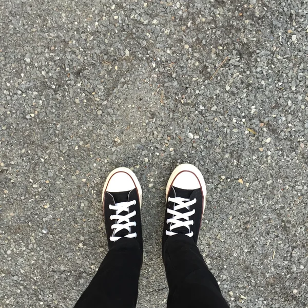 Black sneakers on girl legs. Woman in black jeans and sneakers — Stock Photo, Image