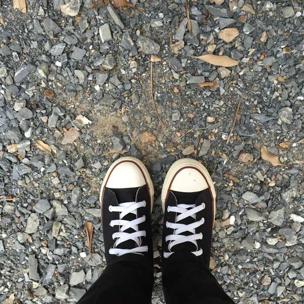 Kız ayak üzerinde siyah spor ayakkabı. Kadın siyah kot pantolon ve spor ayakkabı — Stok fotoğraf