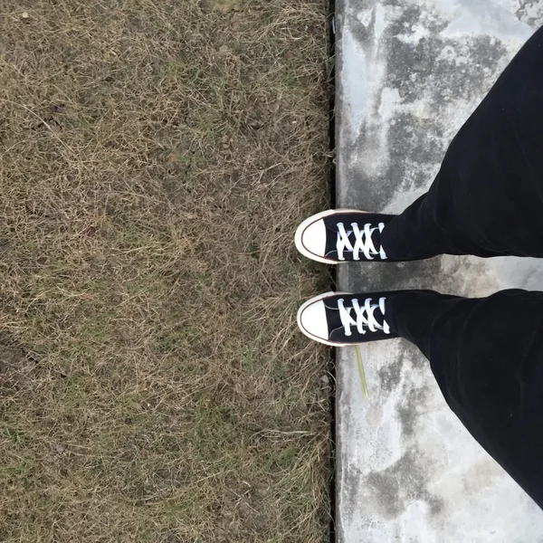 Zwarte sneakers op meisje benen. Vrouw in zwarte jeans en sneakers — Stockfoto