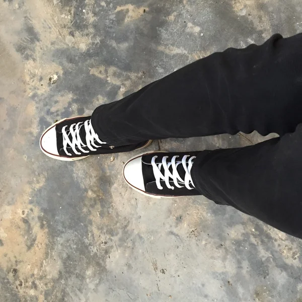 Baskets noires sur les jambes des filles. Femme en jean noir et baskets — Photo