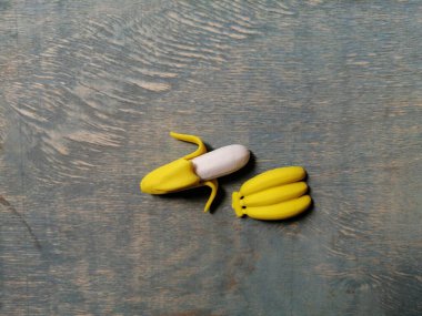 Merkezinde muz dalı olan, donuk mavi ahşap bir zemin üzerinde küçük soyulmuş muz.