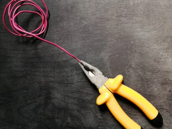 Pliers Yellow Handles Fixed Pink Wire Black Wooden Background — Stock Photo, Image