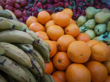 Sokak pazarında meyve satan bir tezgah. çilek, muz, armut, domates, portakal