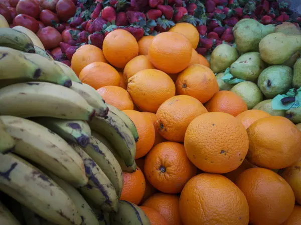 Sokak pazarında meyve satan bir tezgah. çilek, muz, armut, domates, portakal