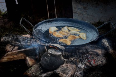 Arjantin 'in kırsal kesimindeki yemek pişirme sahnesinde, altın börekler büyük bir tavada kızartılıyor, yakındaki odun ateşinde, ısıtıcı da ısıtılıyor. Geleneksel Güney Amerika lezzetlerine bir göz atmak kırsal bir yol hazırladı..