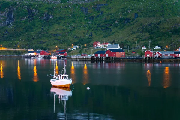 Fischerboot in der Nähe des malerischen Dorfes reine auf lofoten Inseln mit typischer roter Fischerhütte — Stockfoto