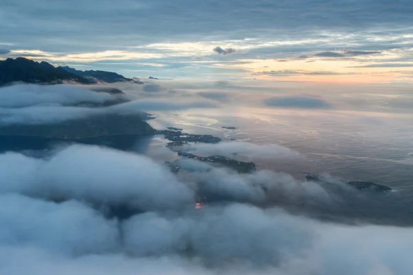 Деревня Рейне в облаках и туман ранним утром. Ночные огни Лофотенса, Норвегия — стоковое фото