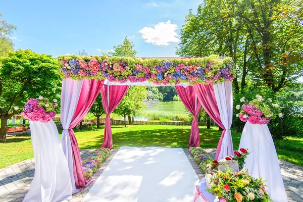 Schöner Hochzeitsbogen mit Blumen im Garten — Stockfoto