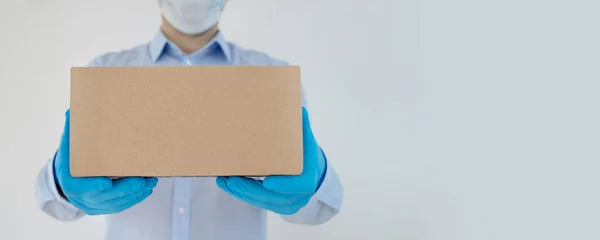 Delivery man holding cardboard boxes in medical gloves and protective mask on white background. coronavirus.