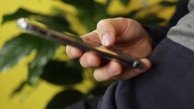 Akıllı telefonlu erkek elleri sarı arka planda. Akıllı telefon ya da dijital aygıt kullanarak internet bankacılığı için kolay ödeme 