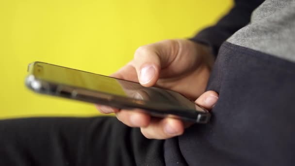 Man handen met smartphone close-up op gele achtergrond. Eenvoudig online bankieren met smartphone of digitaal apparaat, online boeken lezen — Stockvideo